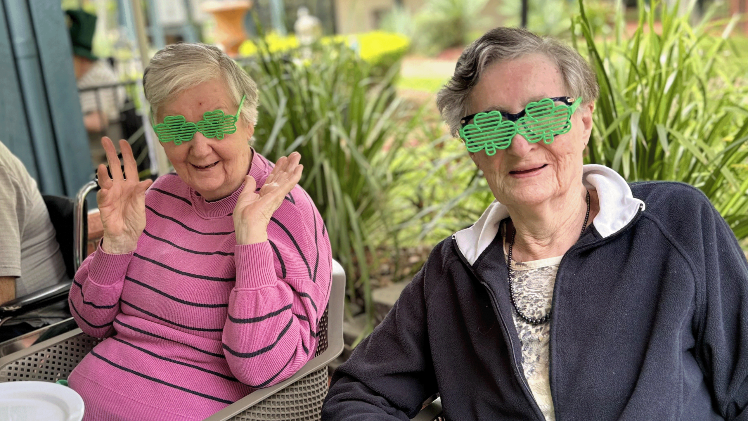 Two smiling women wearing striped green glasses
